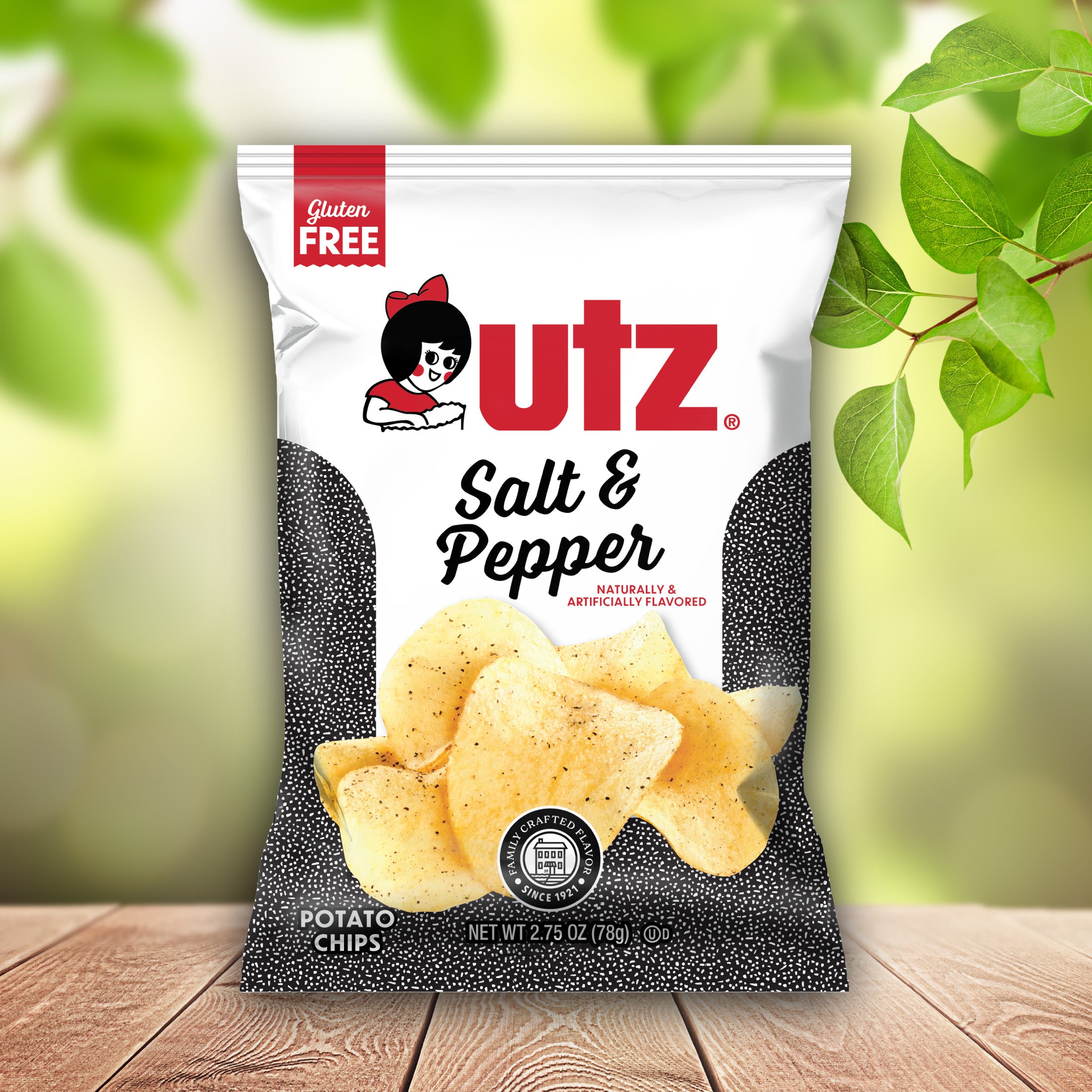 UTZ Salt & Pepper potato chips packaging on a wooden surface with green leaves in the background