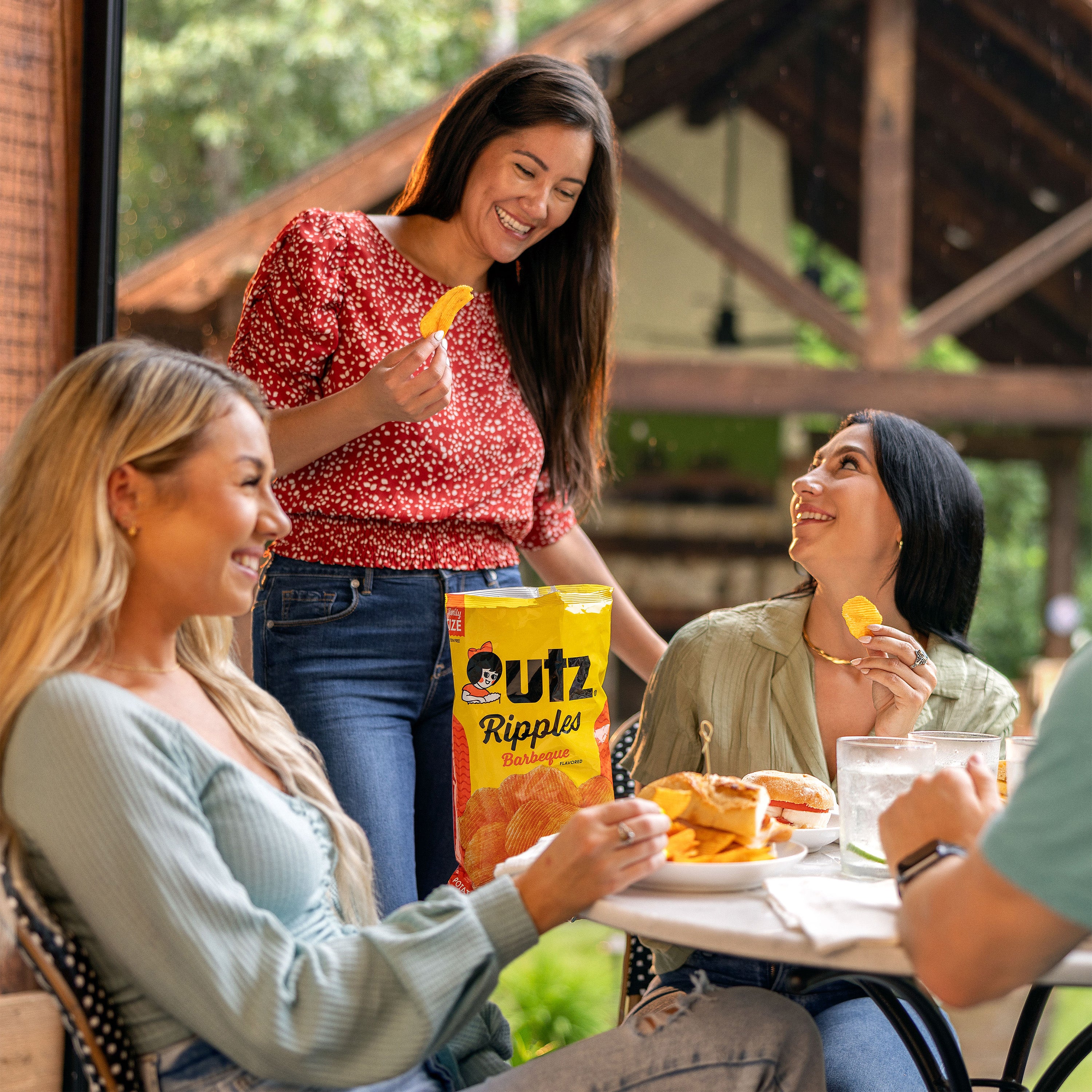 Three women enjoying food outdoors with a bag of Utz Ripples chips.