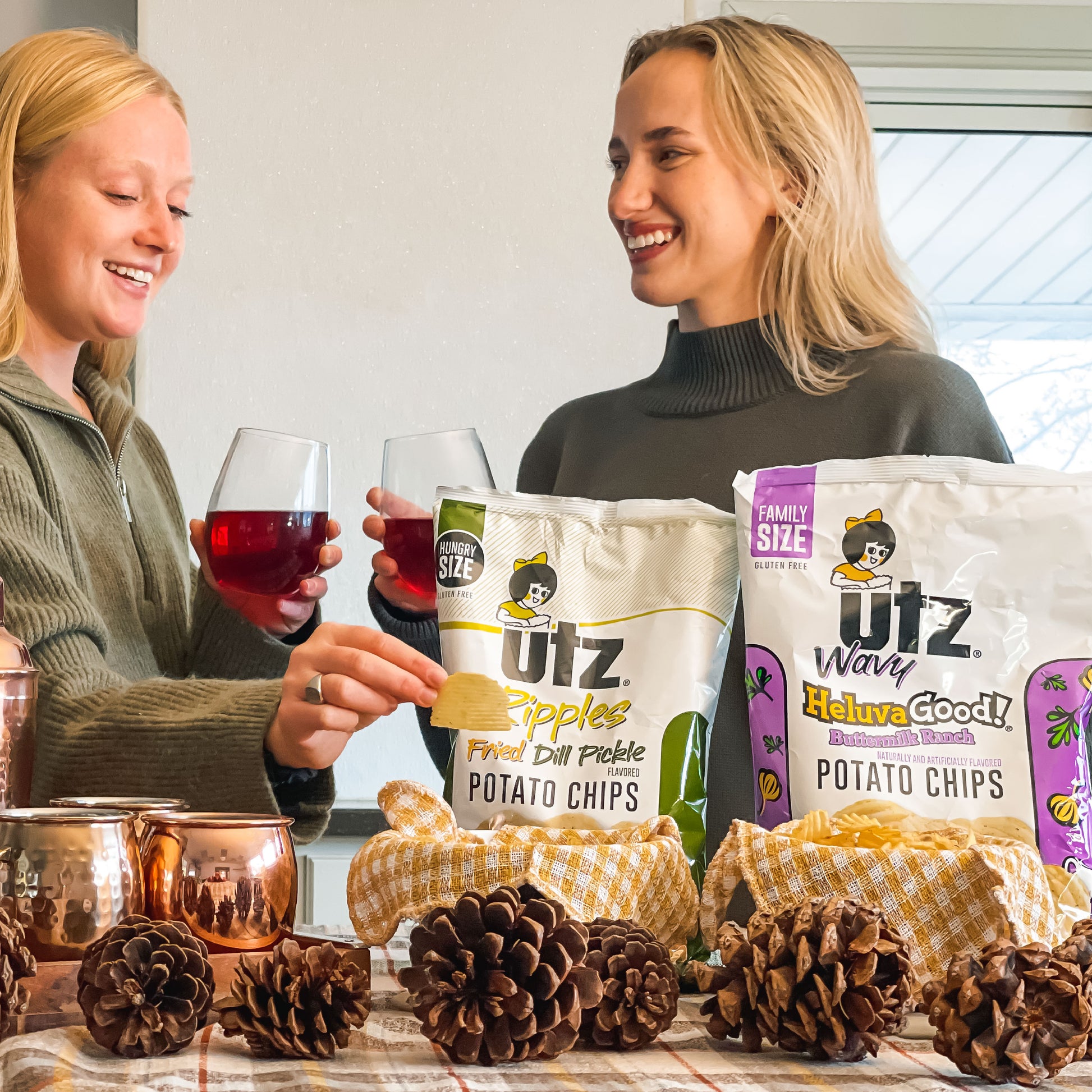 Two women enjoying potato chips and drinks with Utz branded products on a table.