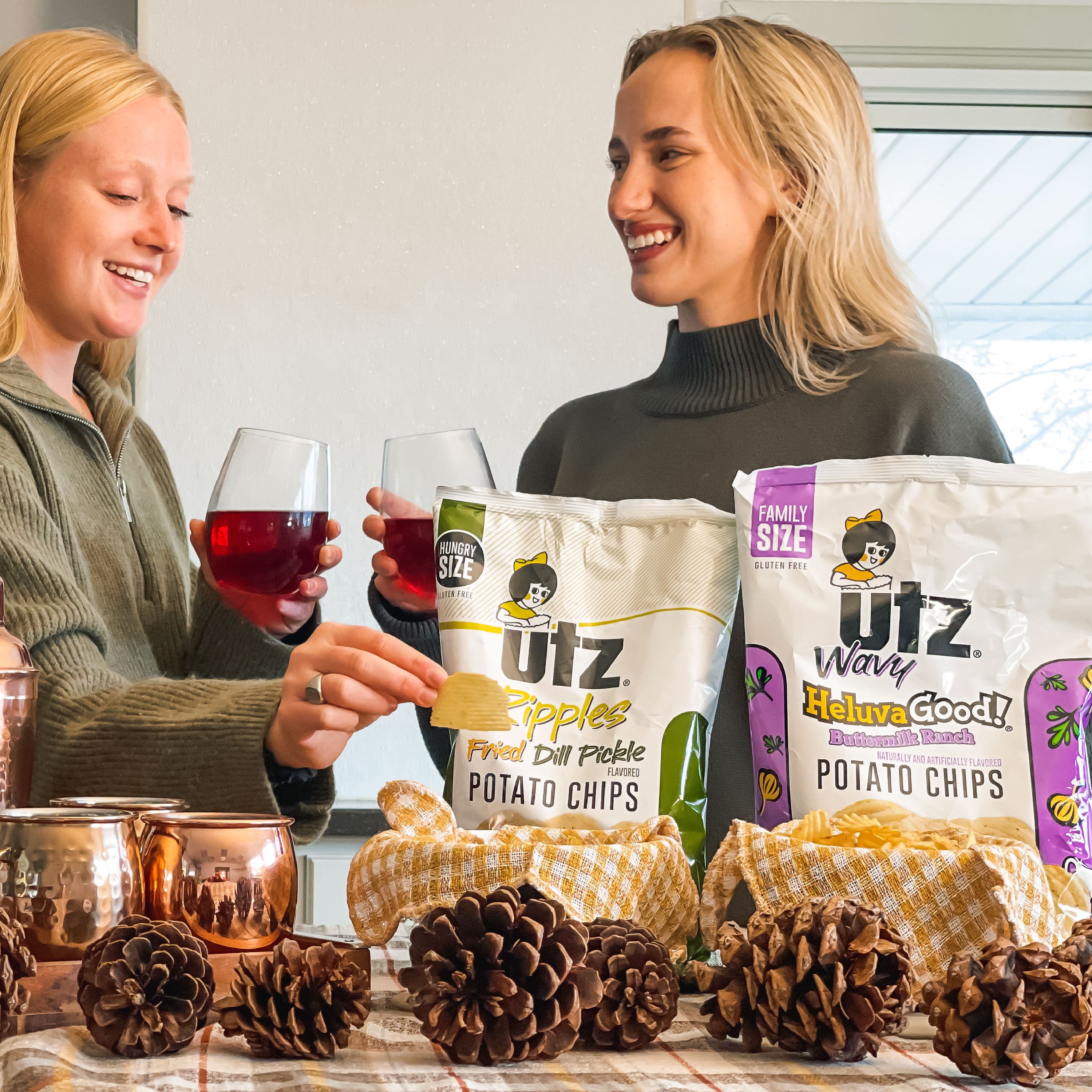 Two women enjoying potato chips and drinks with Utz branded products on a table.