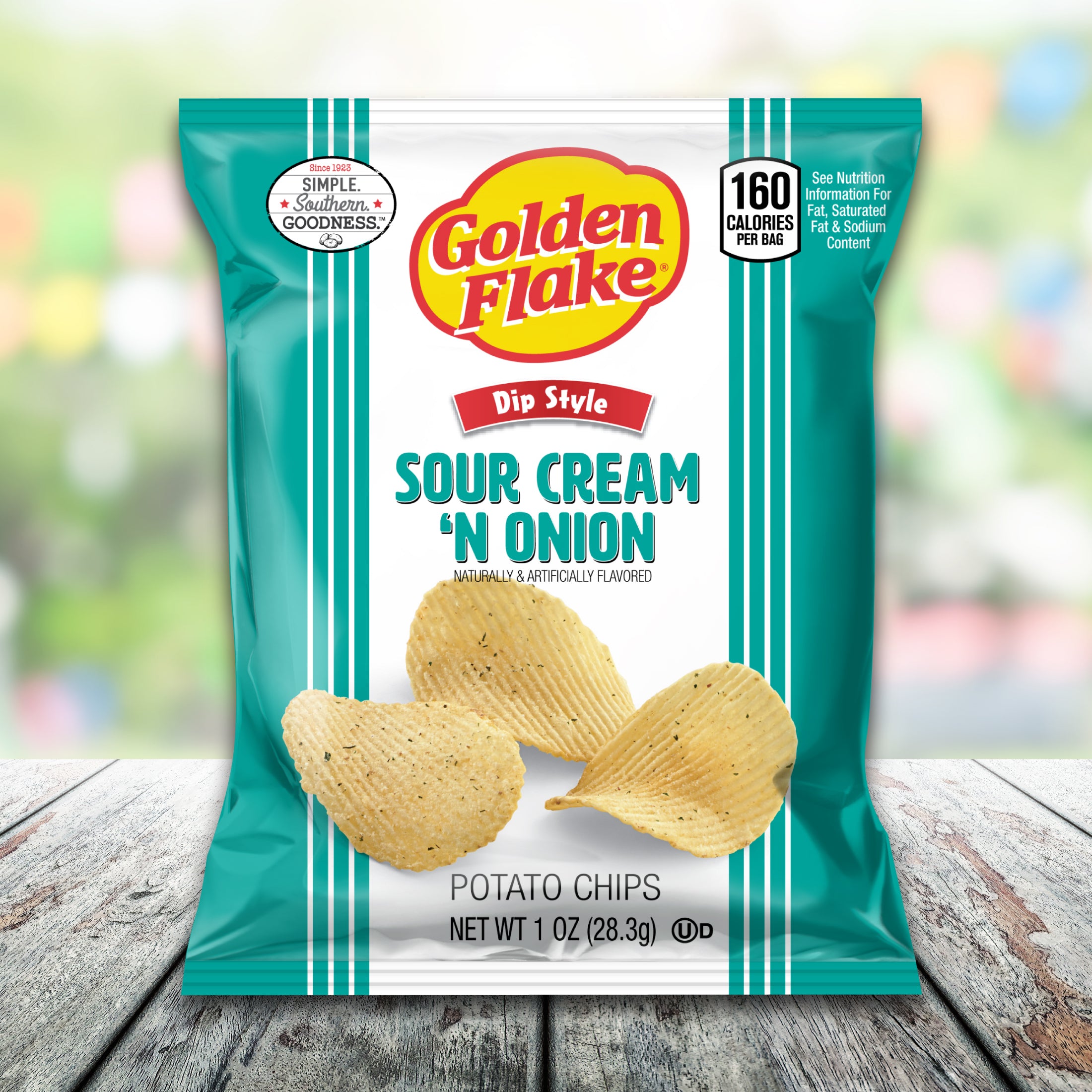 Packaging of Golden Flake Sour Cream 'n Onion potato chips on a wooden surface with a blurred background.