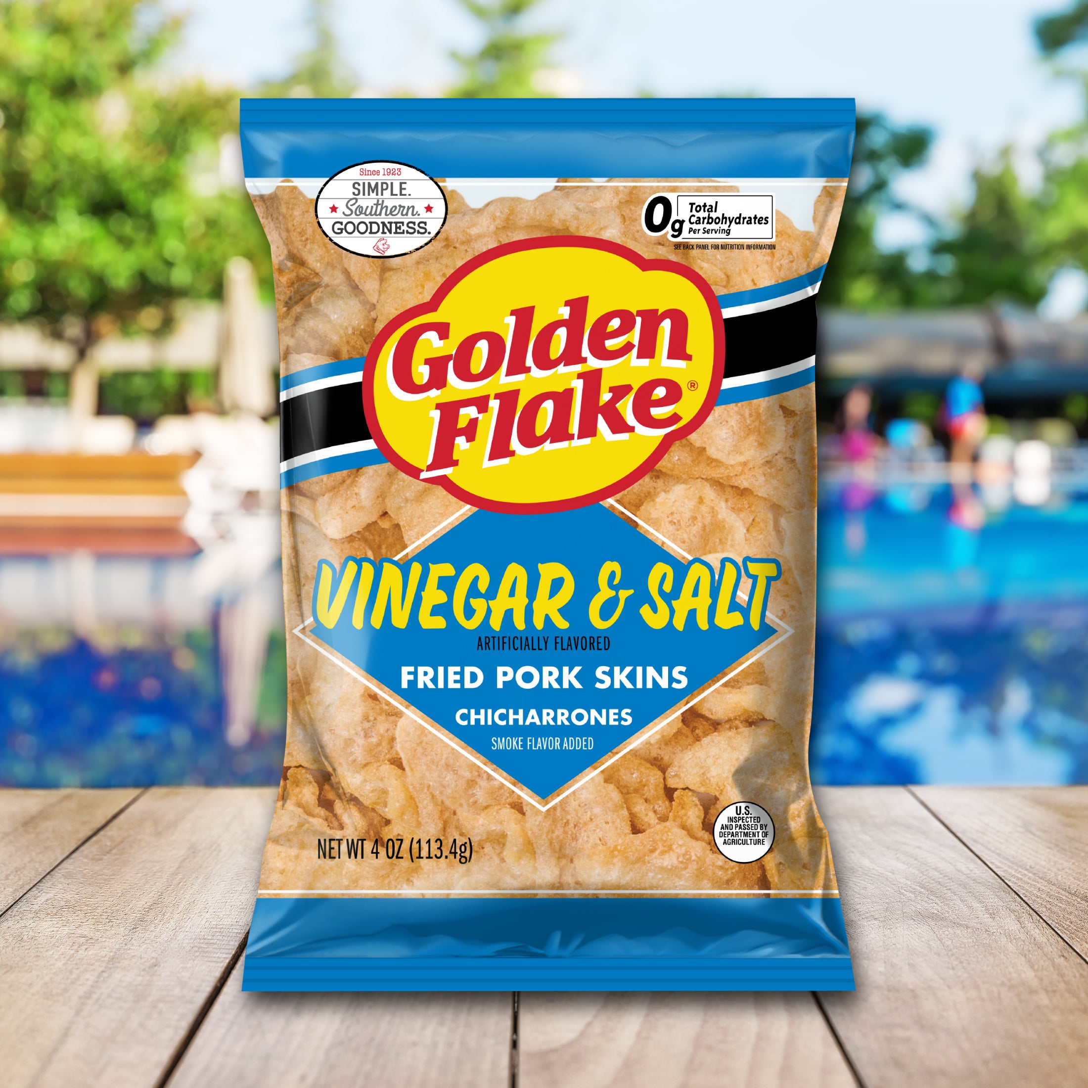 Packaging of Golden Flake Vinegar & Salt fried pork skins on a wooden surface with a blurred outdoor background.