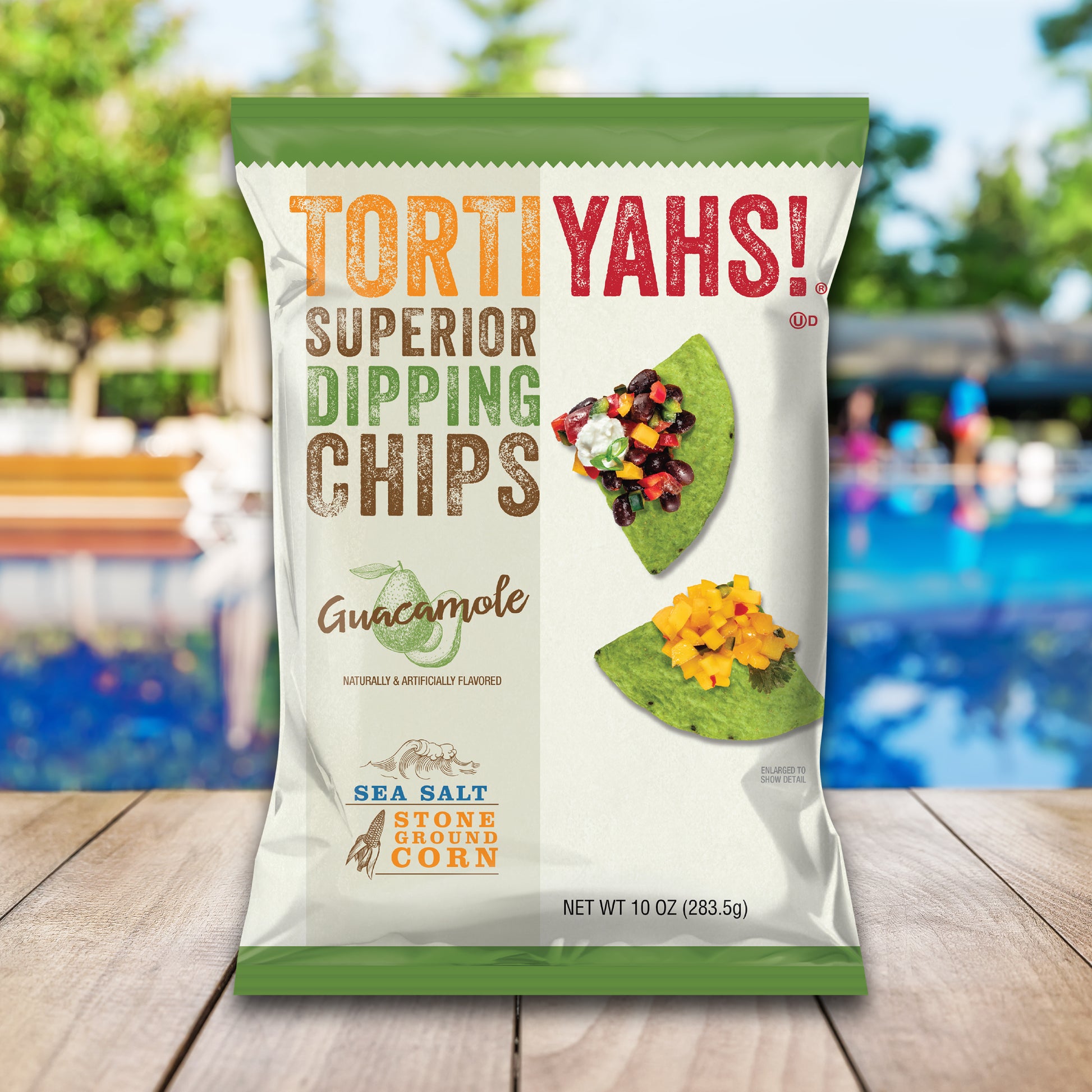 Tortiyahs Guacamole dipping chips packaging on a wooden surface with a blurred outdoor background
