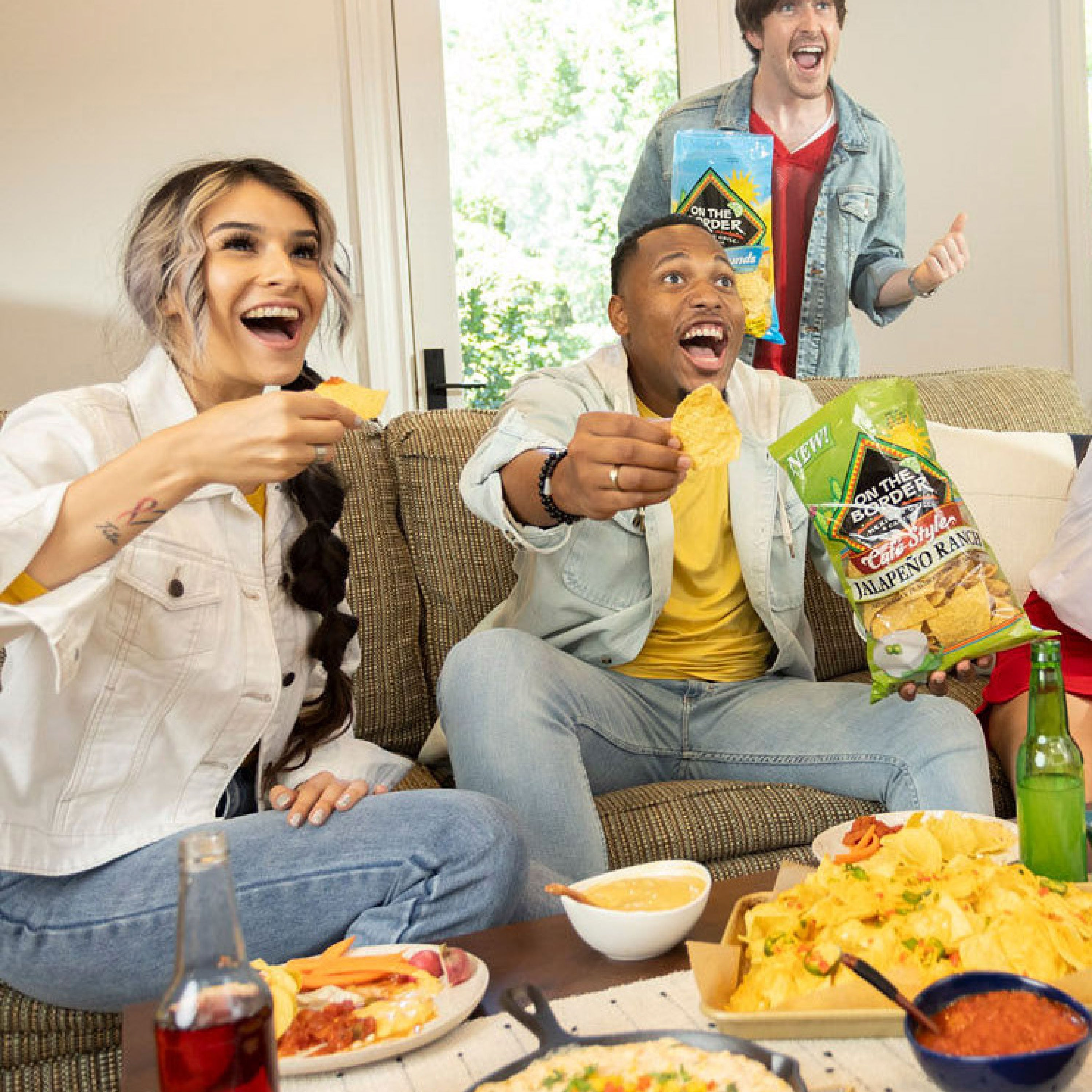 People enjoying snacks and drinks on a couch with a casual setting.