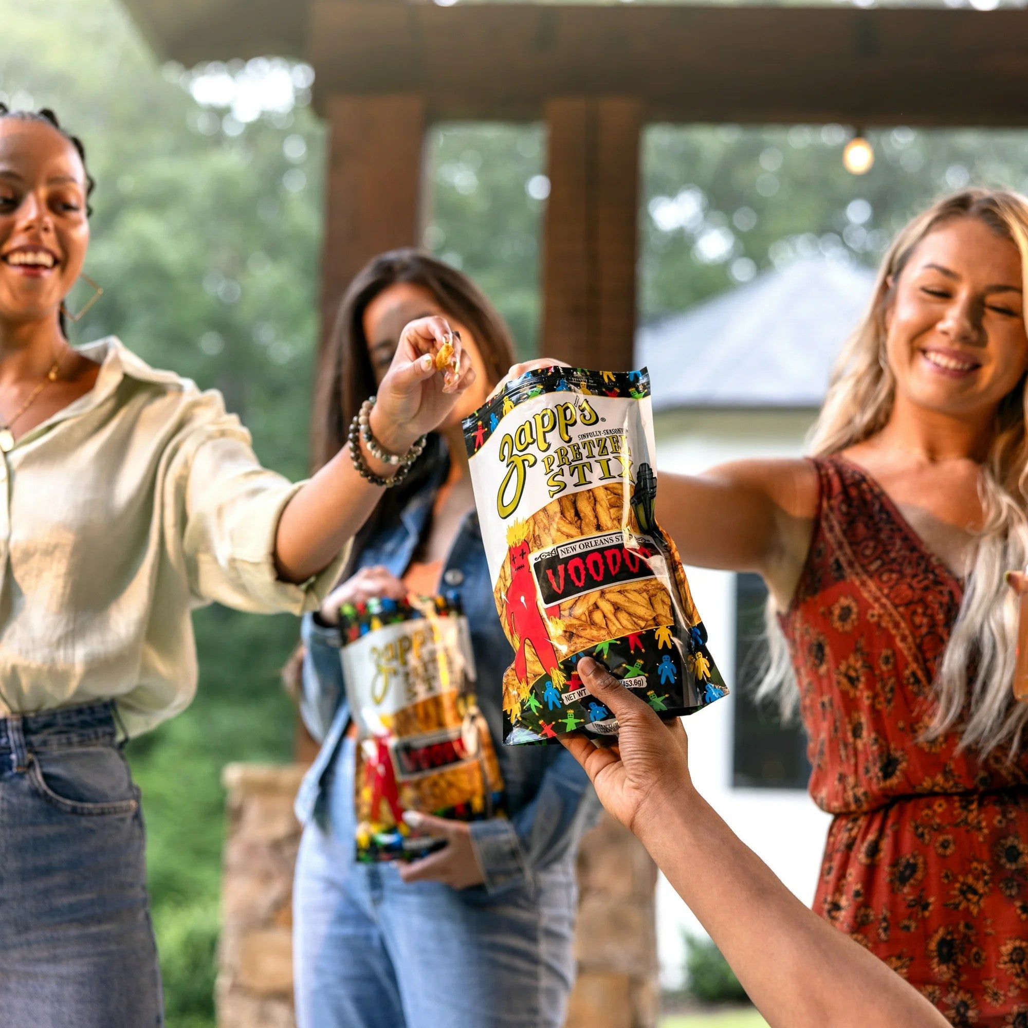 Three women holding bags of Gapp's chips outdoors