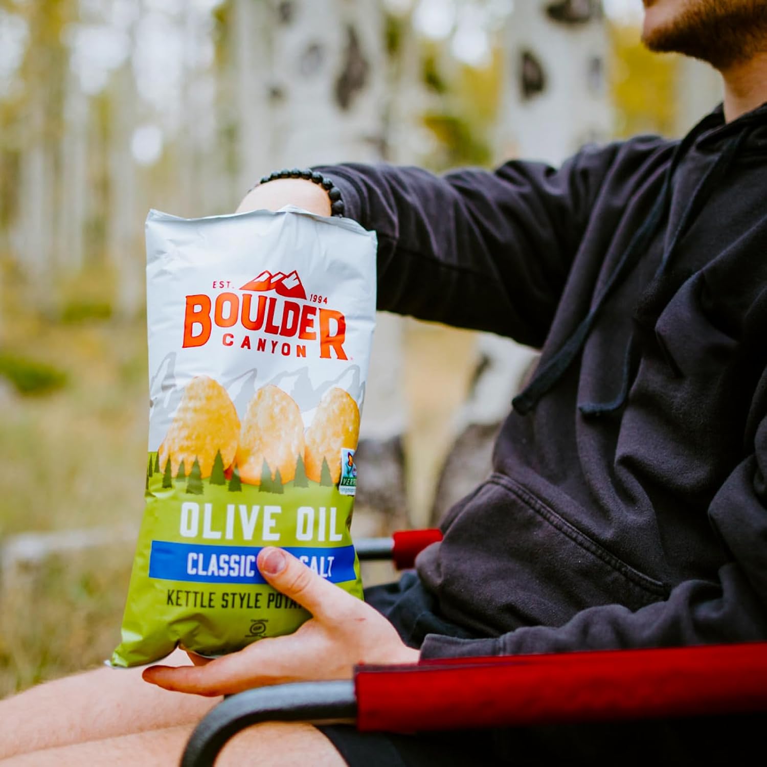 Person holding a Boulder Canyon olive oil kettle style potato bag outdoors.