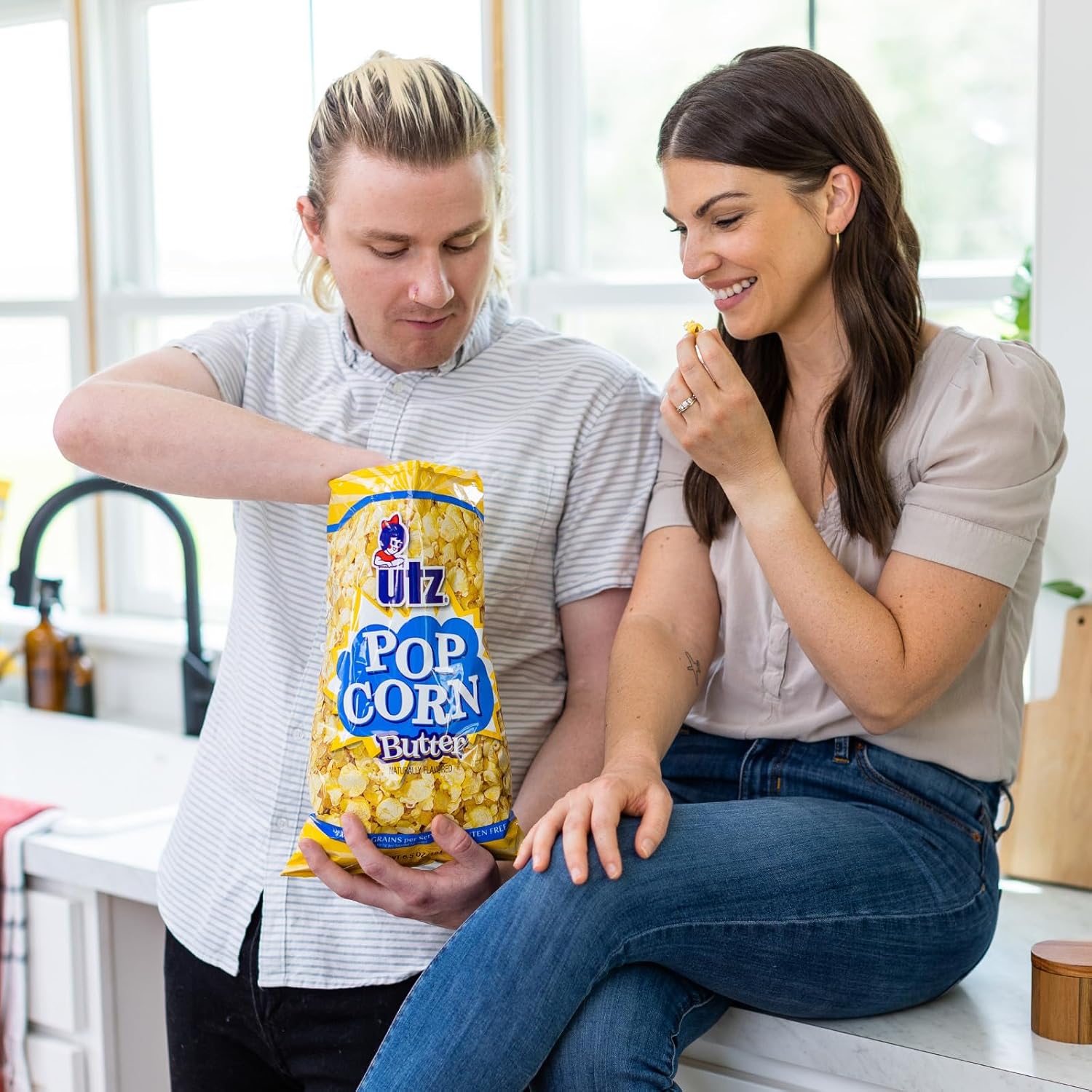 Two people in a kitchen setting with a Ullz Pop Corn Butter bag.