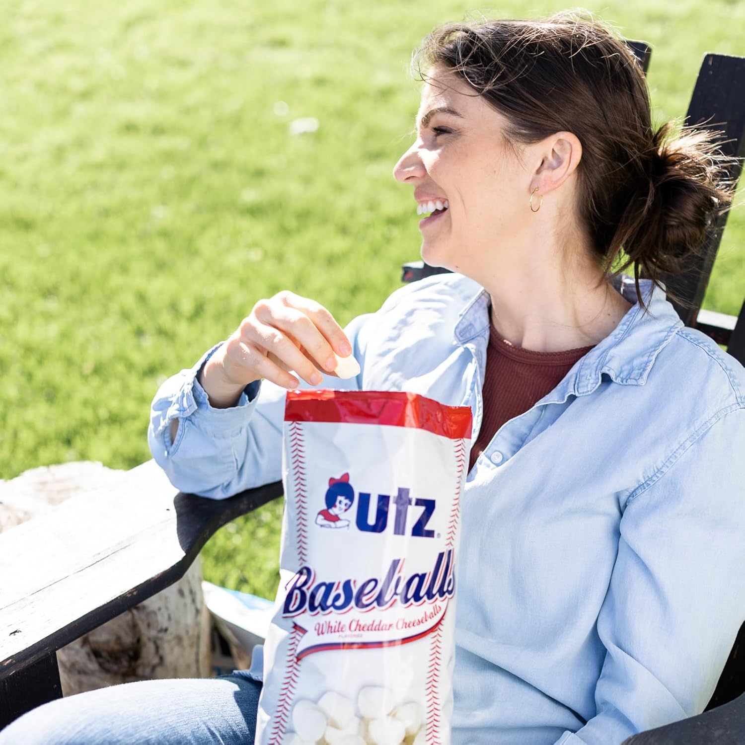 Woman sitting outdoors with a bag of Utz Baseballs popcorn