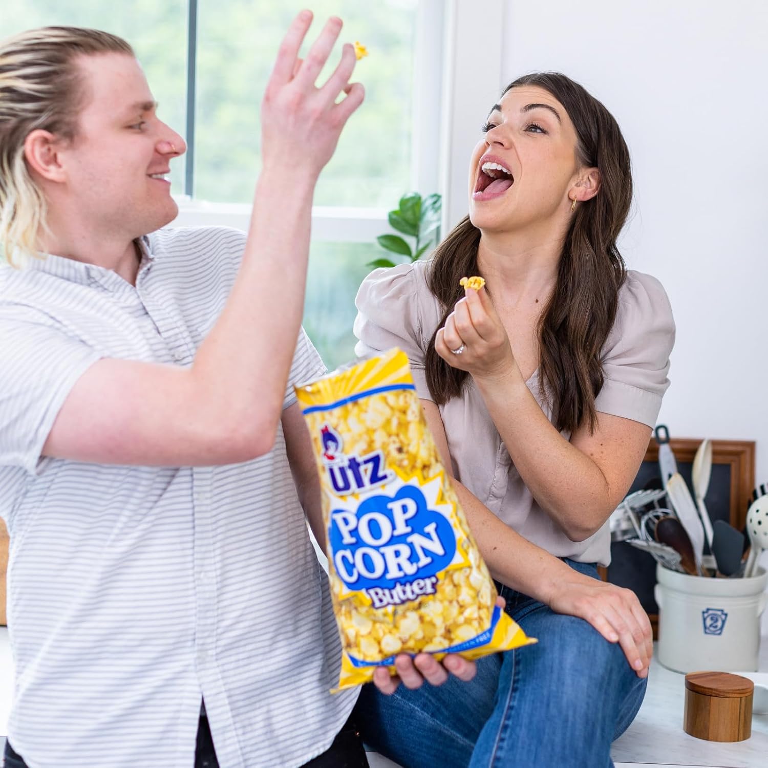 Two people enjoying popcorn with a bag of Lutz Popcorn in a casual setting.