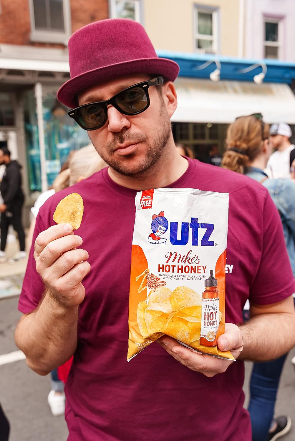 Man holding a bag of Utz Mike's Hot Honey potato chips outdoors.