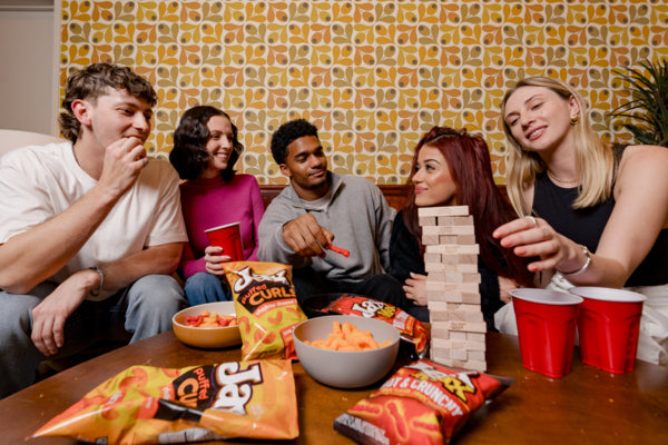 Group of friends playing Jenga with snacks and drinks in a casual setting.