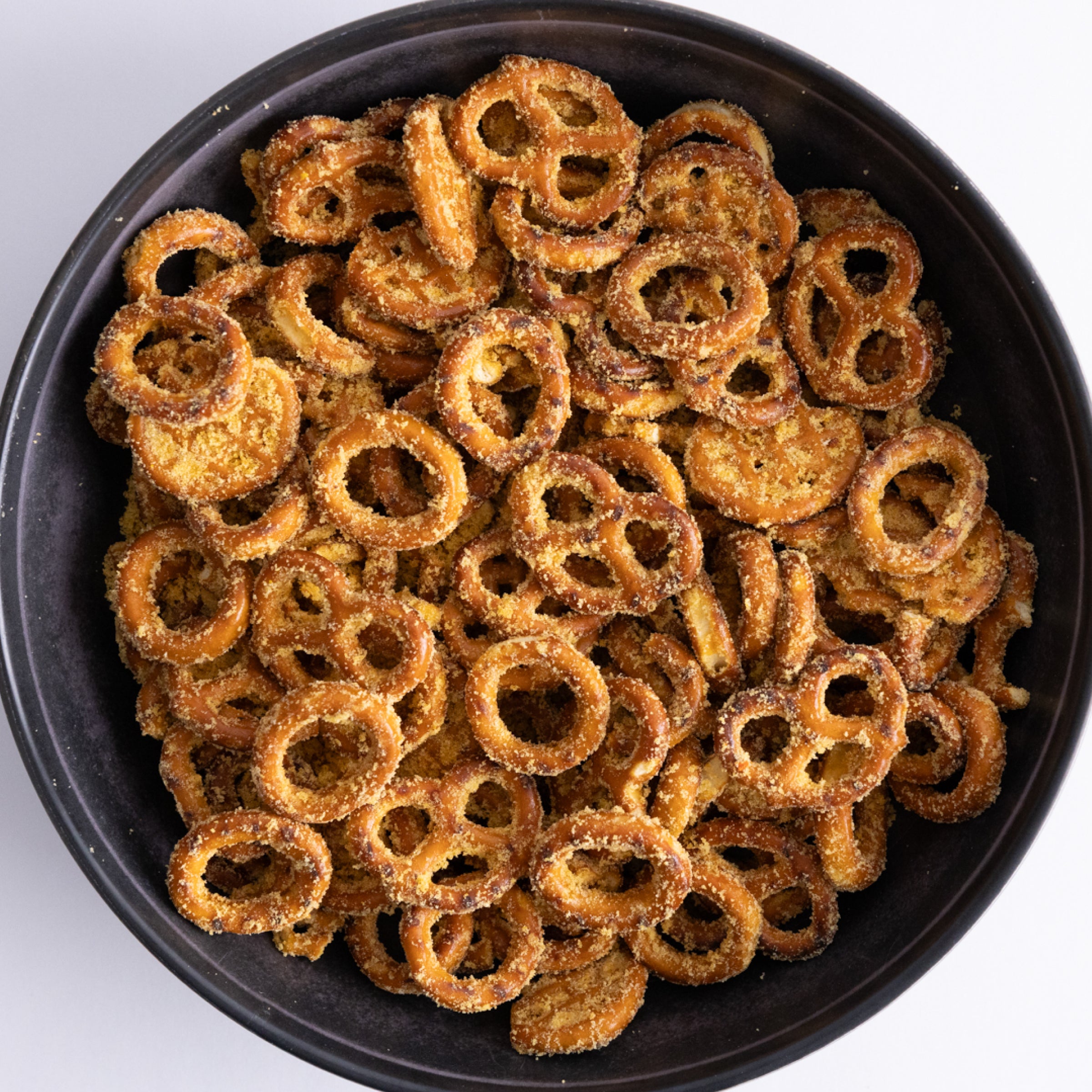 Black bowl filled with pretzel rings on a white background