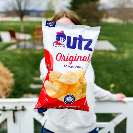 Person holding a bag of Utz Original Potato Chips outdoors