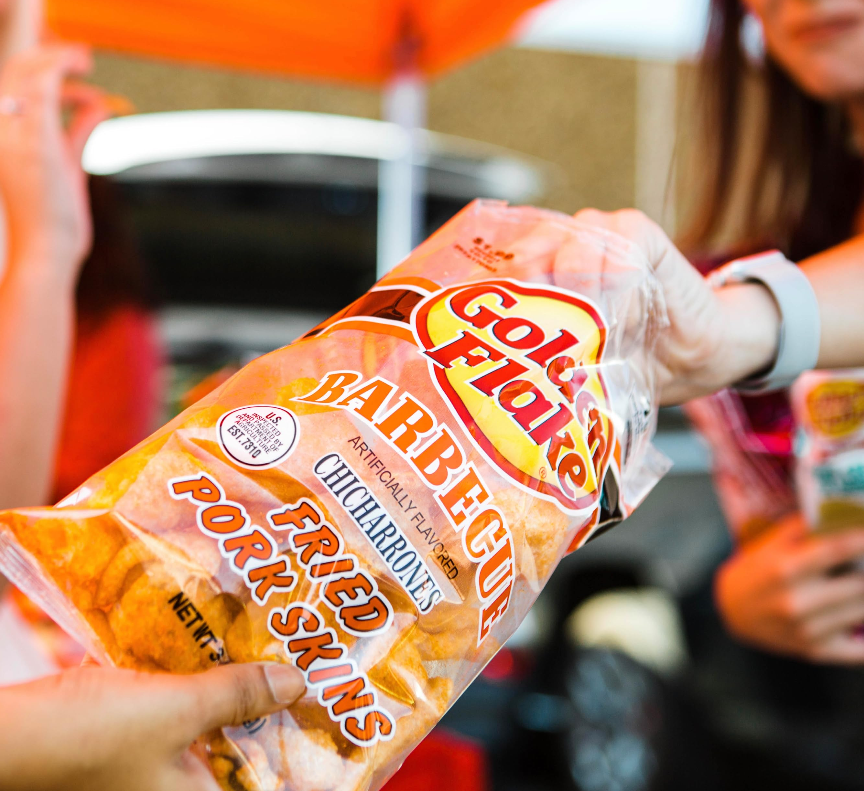 Packaged fried pork skins with 'Gold Medal' branding held by a person.